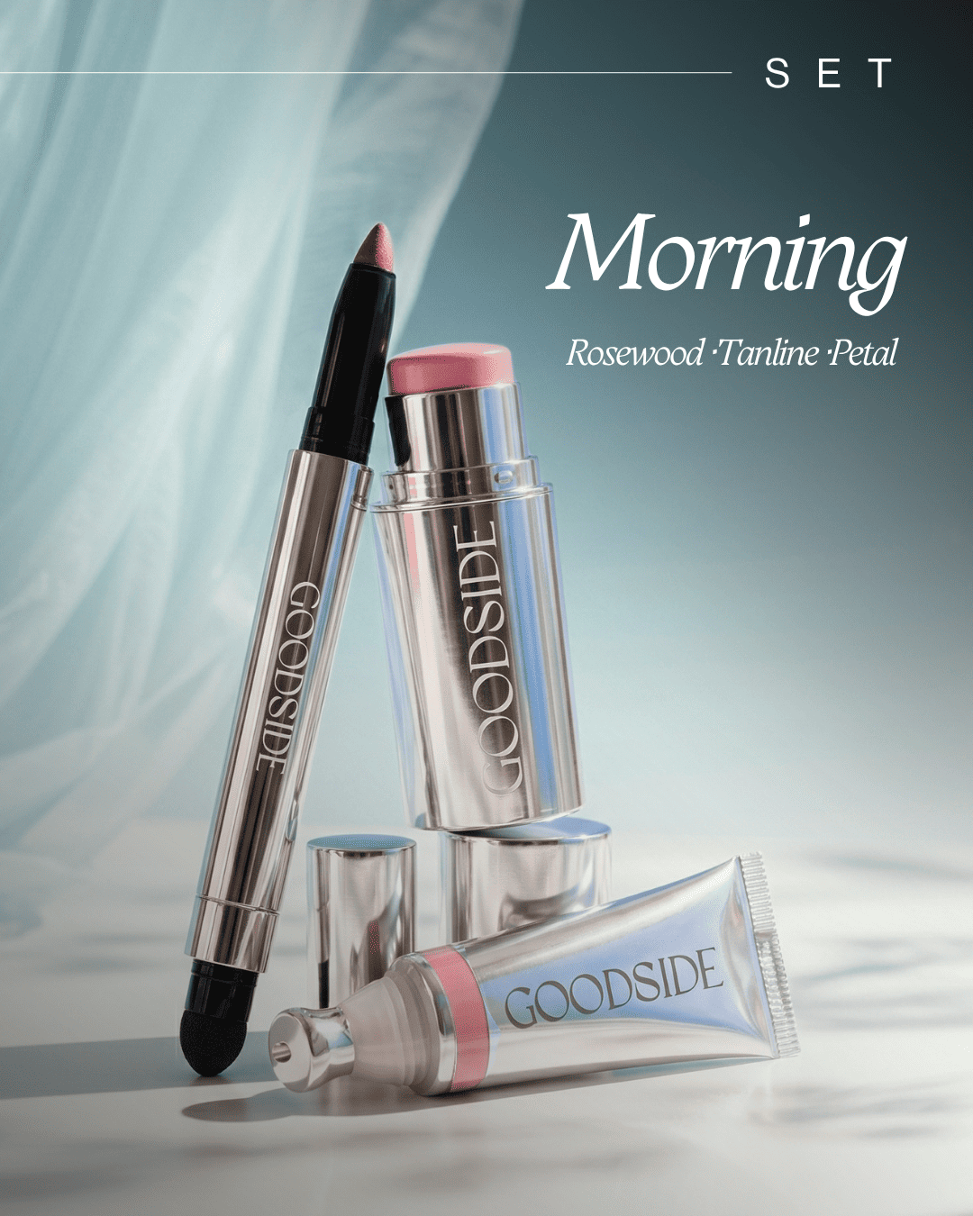 GOODSIDE cosmetic set labeled 'Morning' with rosewood and tanshin powder, featuring a silver lip pencil, a pink-capped stick container, and a silver tube arranged on a soft blue gradient background. - GoodSide